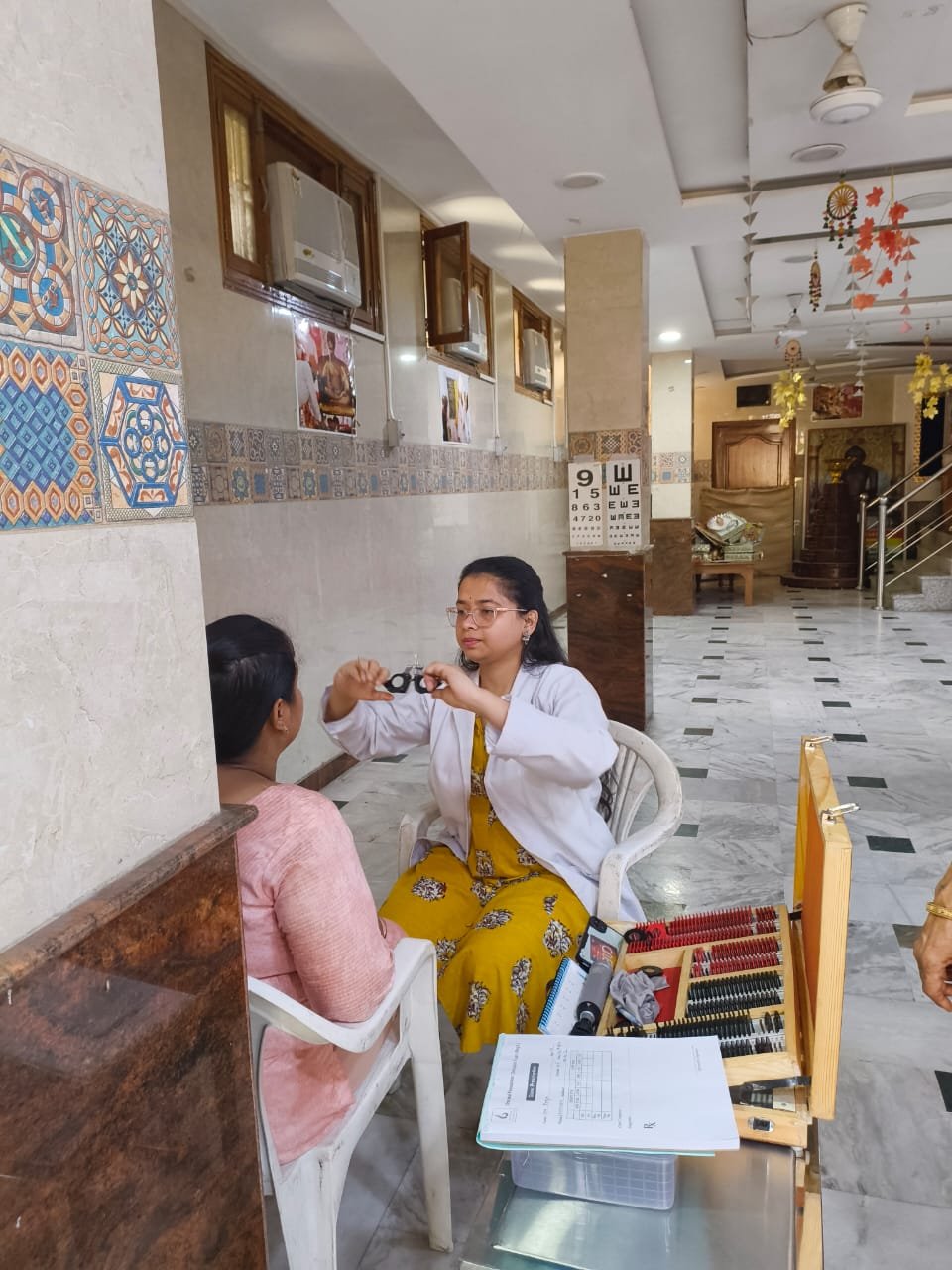 Optometrist fitting trial lenses for a patient at the eye camp